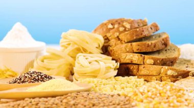 Çeşitli tanecikler, makarna ve ekmek parlak mavi bir arkaplan üzerine dizilmiş, dokuyu ve rengi renklendiriyor.