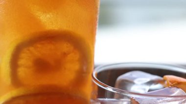 Canlı bir narenciye kokteyline yakın çekim. Taze otlarla süslenmiş. Parlak bir ortamda yoğunlaşma ve buz sergiliyor.