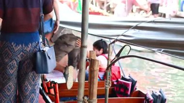 Turistler Bangkok 'un yüzen pazarından bir tekneye biniyorlar