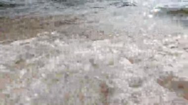 Dalgalar yavaşça kumlu sahile çarpıyor.