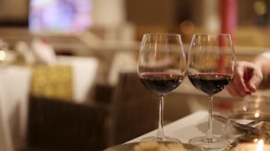 Ilık ve samimi bir atmosfer yaratmak için yumuşak bir restoranda iki kadeh kırmızı şarap tokuşturulur.