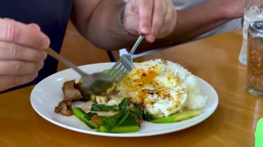 Pirinç ve sebzeli gevrek domuz yiyen kişi.