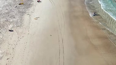 İnsanlar kumsalda güneşli bir günün tadını çıkarıyor.