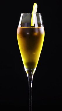 A lemon sour cocktail in a tall glass against a black background, showcasing vibrant colors and elegant presentation