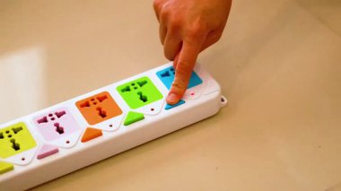 Hand inserts charger into colorful power strip