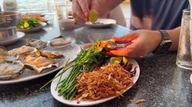 Eller limon ve bitkilerle deniz ürünleri hazırlıyor.