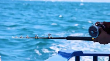 Phuket, Tayland 'da gün ışığında bir kişi tekneden balık tutar. Video, dingin okyanusu ve balık tutma hareketini yakalıyor.