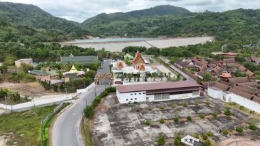 İnsansız hava aracı görüntüleri, Tayland 'ın Phuket kentindeki yemyeşil yemyeşil ve dağlarla çevrili sakin bir Budist tapınağını gün ışığında yakalıyor.