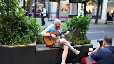 Meşgul bir caddede fotoğraf çekilirken müzisyen gösteri yapıyor