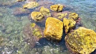 Okyanus dalgaları berrak sulardaki kayalara çarpıyor.