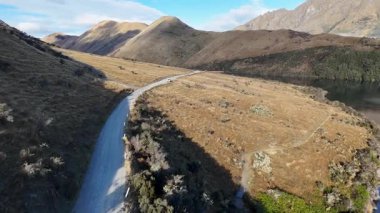 Yeni Zelanda 'nın dağlık arazisinde doğal güzelliği ve dingin çevreyi gösteren dolambaçlı bir yolun havadan görünüşü.