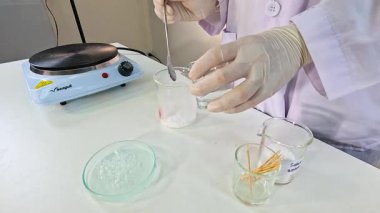 Bilim adamı laboratuvar ortamında beher ve elektrikli ocak kullanarak sodyum asetat kristalizasyonu yapıyor.