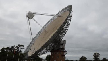 Bulutlu gökyüzü altında dönen büyük radyo teleskop çanağı