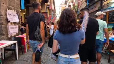 Kalabalık bir sokakta yürüyen ve yemek yiyen insanlar