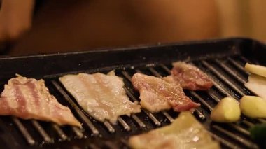 Izgarada cızırdayan domuz pastırması ve sebze.