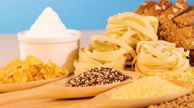 Değişik doku ve şekilleri vurgulayan, parlak bir arkaplan karşısında tahıl, makarna ve ekmek renkli bir düzenleme