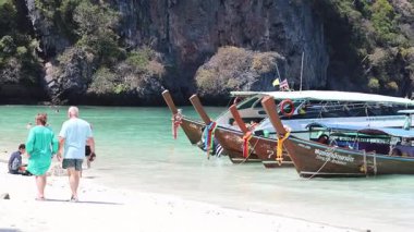 İnsanlar tropikal bir sahilde karaya çıkar ve yürür.
