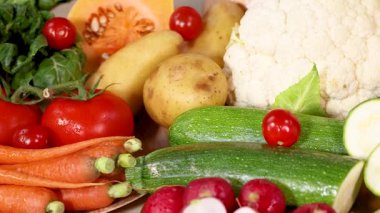 Canlı bir taze sebze çeşidi sanatsal olarak düzenlenmiş, çeşitli renk ve dokuları doğal ışıklandırmada sergiliyor.