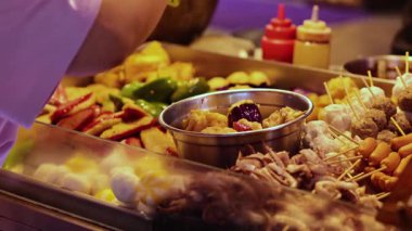 Satıcı yemek standında şiş hazırlıyor.