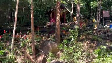 Colorful spirit house surrounded by nature and offerings