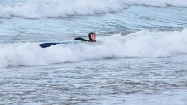 Genç çocuk sörf yapıyor ve dalgalar halinde düşüyor