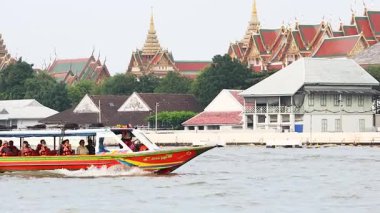 A boat travels past a riverside temple in Bangkok