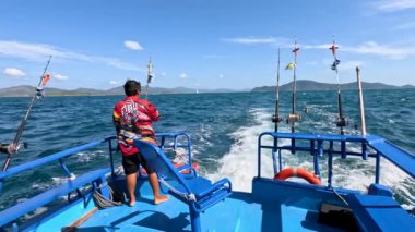 Biri hareketli bir tekneden canlı Phuket sularında olta atar ve balık avlama gezisinin özünü yakalar.