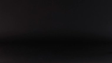 Sarı bir top karanlık bir yüzey boyunca yuvarlanıyor.