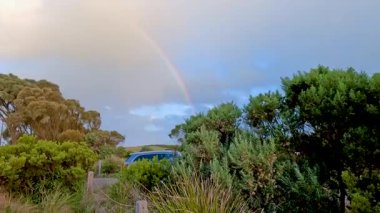 Avustralya 'da yemyeşil bir arazi üzerinde canlı bir gökkuşağı, yumuşak, doğal ışıklandırma altında yakalanır.