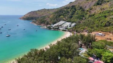 İnsansız hava aracı görüntülerinde Phuket, Tayland 'daki Nai Harn Sahili, turkuaz sular, yemyeşil alanlar ve parlak gün ışığında demirlemiş tekneler görülüyor.