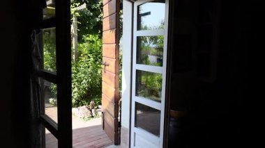 Açık kapı, yemyeşil bahçeyi ve bankı gösterir.