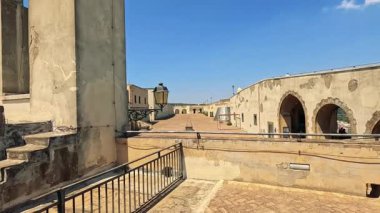 Ziyaretçiler güneşli bir kale avlusunda yürüyor