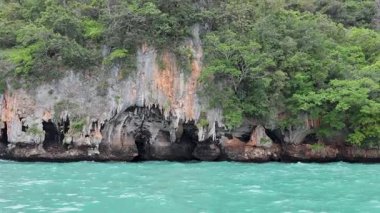 Uzun kuyruklu tekne yemyeşil uçurumları ve turkuaz suları geçiyor.