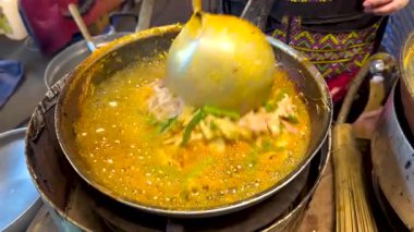 Canlı bir sokak satıcısı, Bangkok 'un hareketli ortamında taze malzemeler ve dinamik pişirme teknikleri sergiliyor.