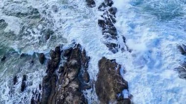İnsansız hava aracı görüntüleri güçlü okyanus dalgalarının doğal gün ışığı altında engebeli, kayalık bir kıyıya çarpmasını kaydeder.