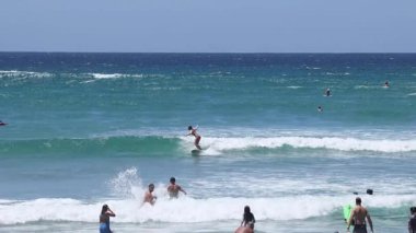 İnsanlar sahilde okyanus dalgalarının tadını çıkarıyorlar.