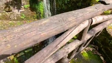 Tahta köprü ve yeşillik yakınında küçük bir şelale.