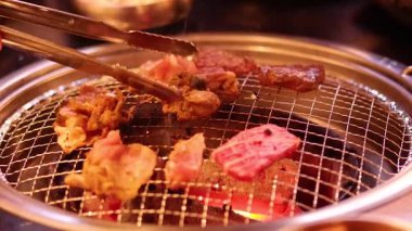 Barbeküde maşayla et kızartılıyor.