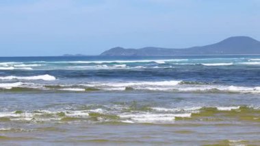 Dalgalar sakin bir plaja hafifçe çarpıyor.