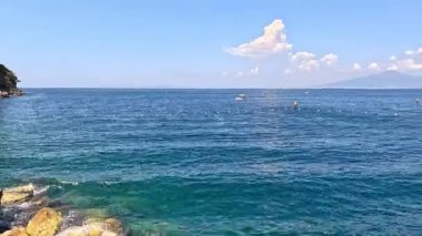 Sakin deniz, uzak dağlar ve bulutlar