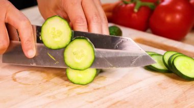 Arka planda domatesli salatalık doğrayan eller.