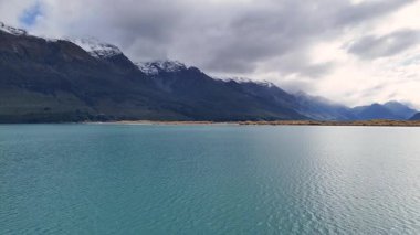 Bulutlu gökyüzünün altında sakin bir göl. Glenorchy, Yeni Zelanda 'da doğal güzellik ve sakinlik sergiliyor.