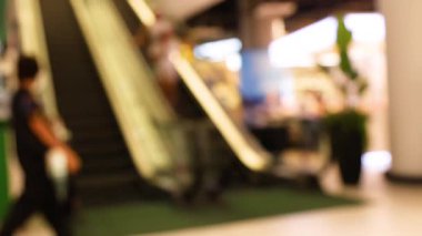 İnsanlar alışveriş merkezinde yürüyen merdiven kullanıyor.