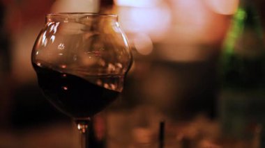 Loş bir ortamda kırmızı şaraplı bir şarap kadehi samimi ve samimi bir ortam yaratıyor.
