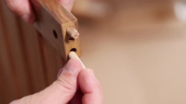 Eller tahtaya bir panel yerleştirir, çekiçle emniyete alır. Yakından bakıldığında hassasiyet ve işçilik vurgulanıyor