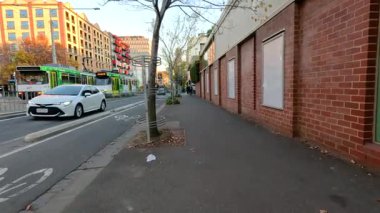 Tramvay, yayalar ve tuğla binaların yer aldığı kentsel sokak manzarası