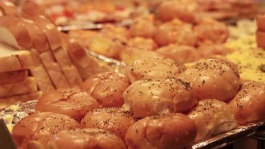 Kalabalık bir pazarda çeşitli ekmekler sergileniyor