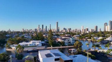 İnsansız hava aracı görüntüleri, açık mavi gökyüzü altındaki su yollarının, yerleşim alanlarının ve gökdelenlerin altını çizerek, Avustralya 'nın Gold Coast kentsel manzarasını yakalar.