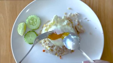 Kaşık ve çatal yumurta sarısını pirinç üzerinde kırar.