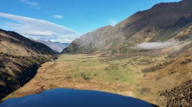 Moke Gölü 'nün yeni Zelanda, Queenstown' daki sakin manzarasını geniş dağ manzaraları ve açık gökyüzü ile görüntüler.